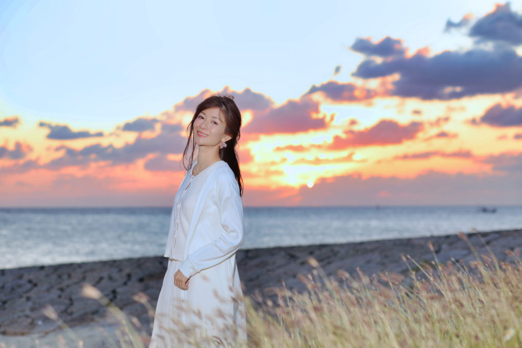 大城優紀が夕暮れのちゅらさんビーチの中、笑っているポートレート写真